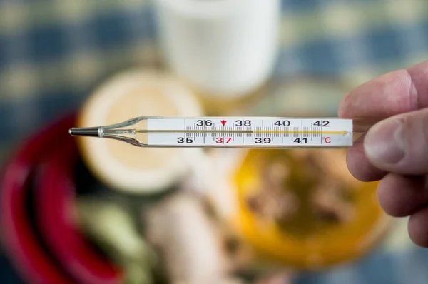 mercury thermometer with high temperature over healthy food  background.