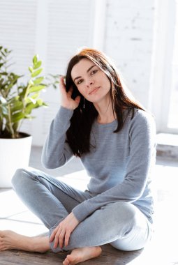 Kot pantolonlu genç ve çekici bir kadın evinin penceresinin karşısında oturuyor.