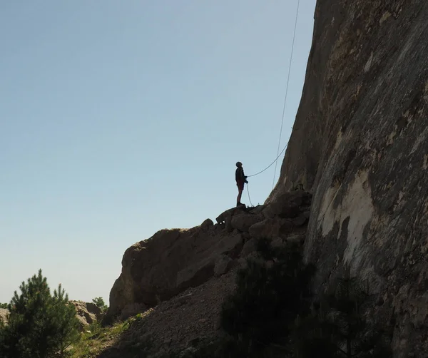 Ορειβάτης είναι ο έλεγχος ρελέ σχοινιά στο άκρο της απότομη πλαγιά του βουνού — Φωτογραφία Αρχείου