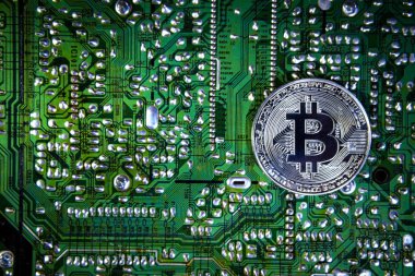 bit-coin is made of expensive metal on the electronic circuit Board green 