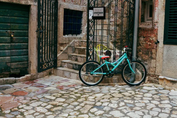 KOTOR, MONTENEGRO, 21 de septiembre de 2016: la bicicleta está aparcada en la puerta de la parrilla del apartamento en el casco antiguo de Kotor — Foto de Stock