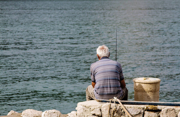 KOTOR, MONTENEGRO, September 21, 2016: man fishing sitting on the pier.