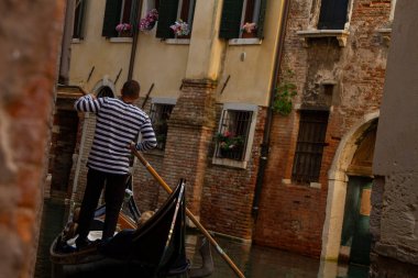 Venedik gondolcusu turistleri Venedik kanallarında gezdiriyor.