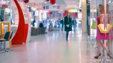 Genç kız alışveriş merkezinde deposundan çıkar. Etrafa kız ve mağaza yaprakları.