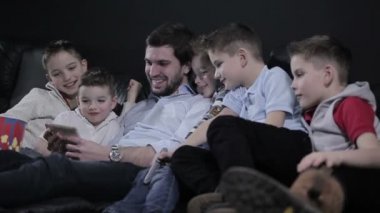 Adam ve çocuklar video smartphone içinde arıyoruz. Çocuklar gülüyor. Adam gülümseyen.