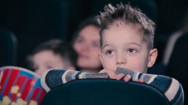 Küçük çocuk koltuk arkası karşı eğildi. Film izlerken ve sinemada screamin çocuk.