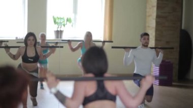 Bir grup insan çubuklarla egzersizleri yapıyor