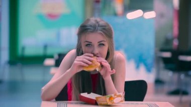 Kız aç. Genç Kız dağınık bir humburger Cafe'de yemek ve bir ağız el ile silin.