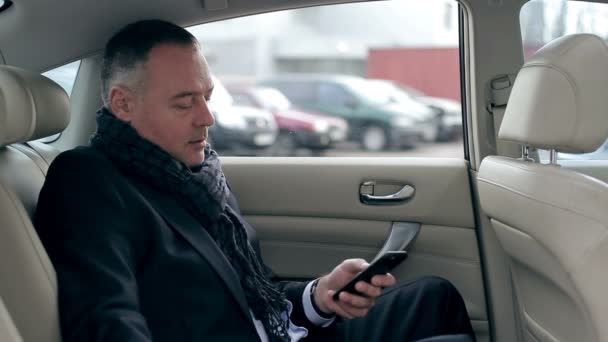 Бизнесмен сидит на заднем сиденье автомобиля — стоковое видео