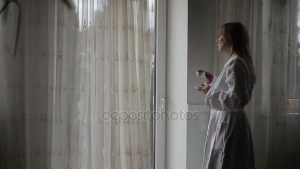 Jolie femme regardant par la fenêtre . — Video