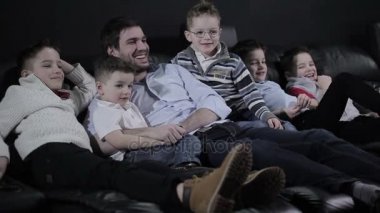 Adam çocuklu sinema kanepede döşenmesi. Adam ve 5 erkek gülerek ve gülümseyerek.