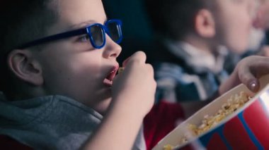 Sinemada patlamış mısır yemek ve film izlerken çocuklar.