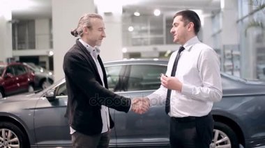 Araba Bayilik başarılı anlaşma. Bir araba bir satıcıdan satın almak bir erkek. Alıcı ve satıcı arasındaki karşılıklı. Araba satıcı üzerinde anahtar araba Bayilik içinde alıcıya teslim.