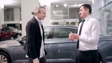 Araba Bayilik başarılı anlaşma. Bir araba bir satıcıdan satın almak bir erkek. Alıcı ve satıcı arasındaki karşılıklı. Araba satıcı üzerinde anahtar araba Bayilik içinde alıcıya teslim.