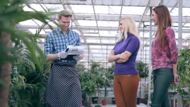 Květinářství slouží zákazníkům ve skleníku. — Stock video