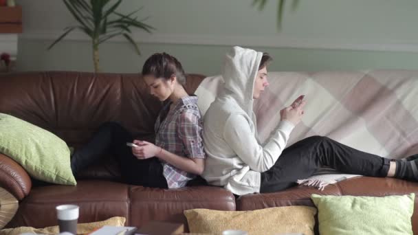 Pareja se sienta espalda con espalda en el sofá — Vídeos de Stock