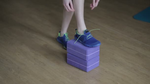 Дівчина зв'язує шнурки в спортзалі — стокове відео