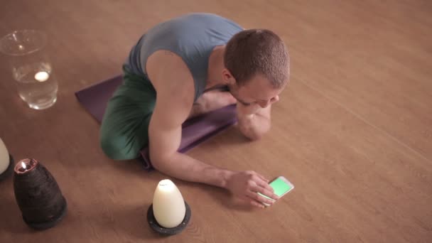 Man met behulp van de telefoon tijdens yoga — Stockvideo