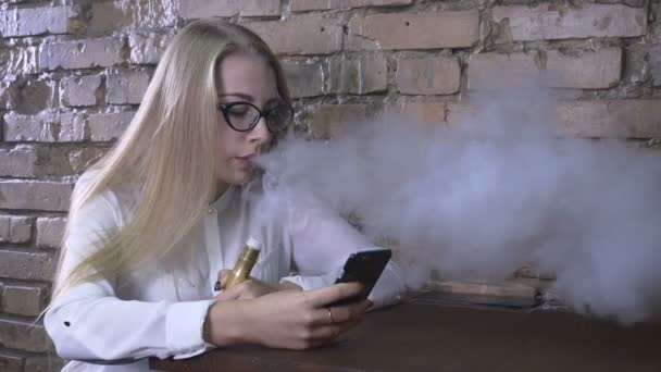 Fata tânără fumează țigară electronică și folosește smartphone-ul — Videoclip de stoc