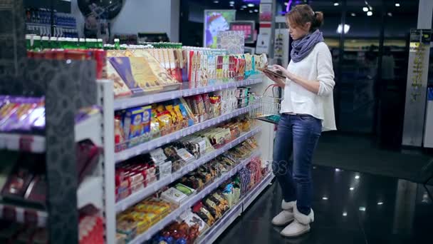 Menina escolhe produtos com um tablet . — Vídeo de Stock