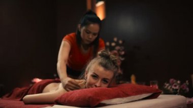 Asyalı kadın kırmızı üniformalı spa salonda geleneksel Tay masajı yapıyor