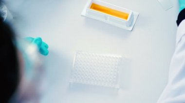 Mavi eldiven ve modern laboratuvarda çalışan beyaz üniformalı kadın 