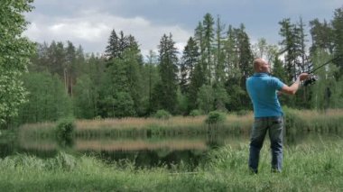 Arkadan mavi gömlek balıkçılık erkekte görünüşü yeşil ormandaki göl kenarında