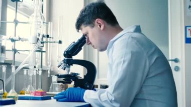 modern laboratuvarda çalışan beyaz üniformalı genç brunet adam 
