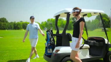 genç adam ve kadın mini golf arabası golf kulübünde yeşil çimenlerin üzerinde