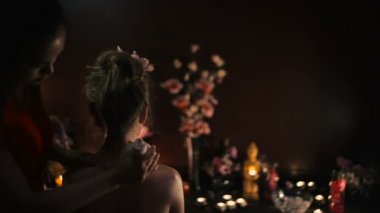 Asyalı kadın kırmızı üniformalı spa salonda sıkıştırma kullanarak geleneksel Tay masajı yapıyor 