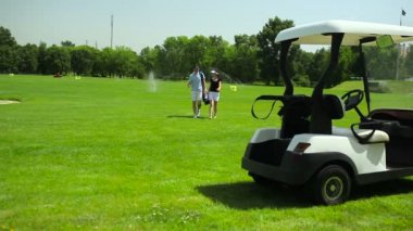 genç adam ve kadın golf kulübünde yeşil çimenlerin üzerinde yürüyüş