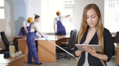Dijital tablet ve gençlerin zemin üzerine mavi çalışma üniforma temiz Office kullanarak iş kadını