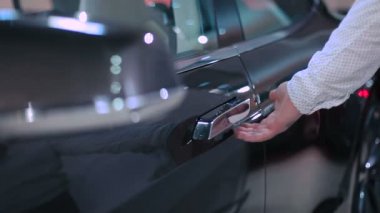 erkek Close-Up el itme modern düğmesini ve yeni siyah araba kapıda aç