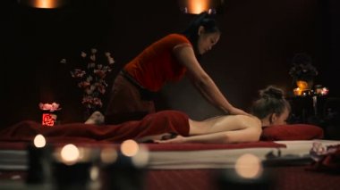 Asyalı kadın kırmızı üniformalı spa salonda geleneksel Tay masajı yapıyor