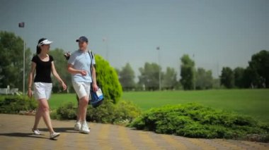 genç adam ve kadın golf kulübünde yeşil çimenlerin üzerinde yürüyüş