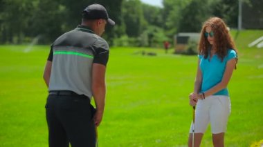 genç adam ve kadın golf golf kulübünde yeşil çimenlerin üzerinde oynamak  