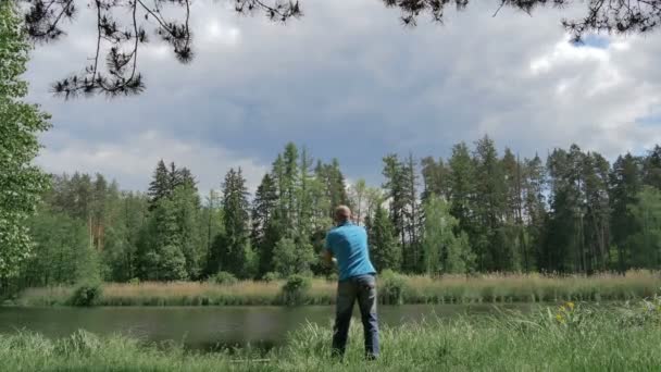 Back View Man Blue Shirt Fishing Lake Green Forest — Stock Video