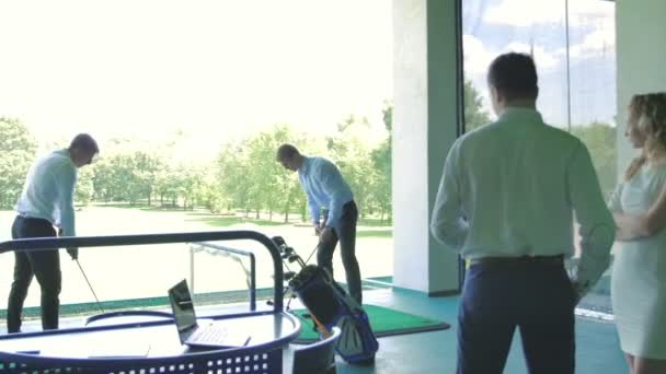 jeunes hommes d'affaires jouent au golf près de femme blonde dans un immeuble de bureaux moderne 