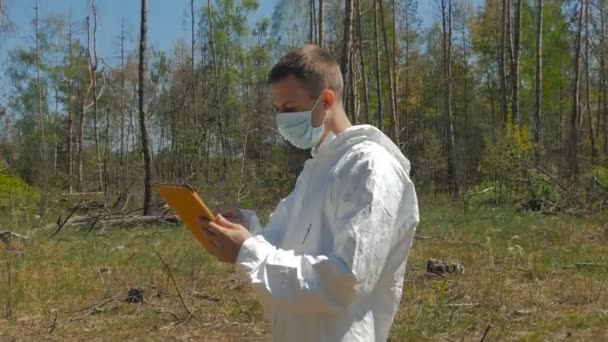 Człowiek Białym Mundurze Maski Pomocą Cyfrowego Tabletu Lesie Słoneczny Dzień — Wideo stockowe