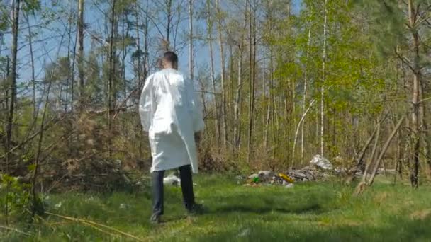 Hombre Uniforme Blanco Caminando Bosque Lleno Basura Día Soleado — Vídeo de stock