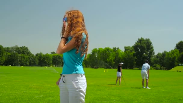 年轻女性使用电话在夏天在高尔夫球俱乐部的背景的人 — 图库视频影像