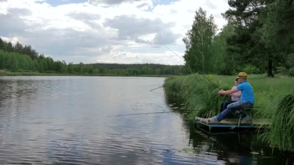 男子与儿子在绿色公园湖捕鱼 — 图库视频影像