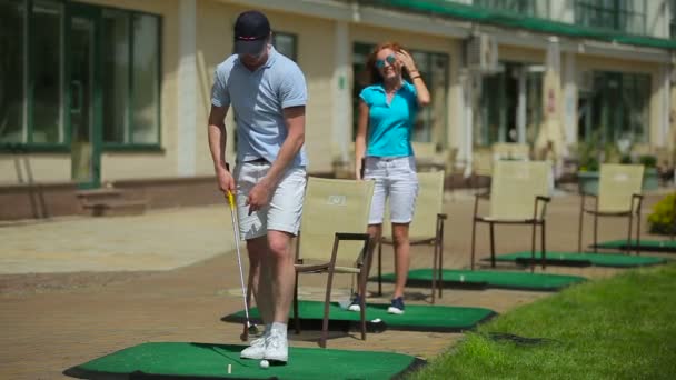若い男と女がゴルフクラブで緑の草の上ゴルフします — ストック動画