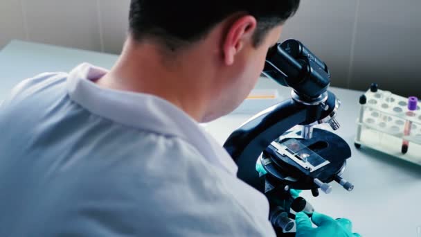 jeune homme brunet en uniforme blanc travaillant dans un laboratoire moderne  