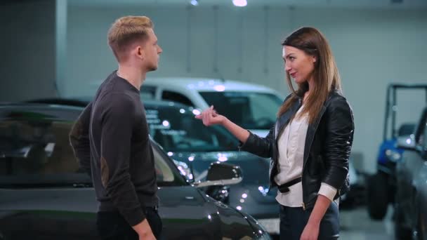 若いカップルのモダンな新車ディーラーから鍵を持つ — ストック動画