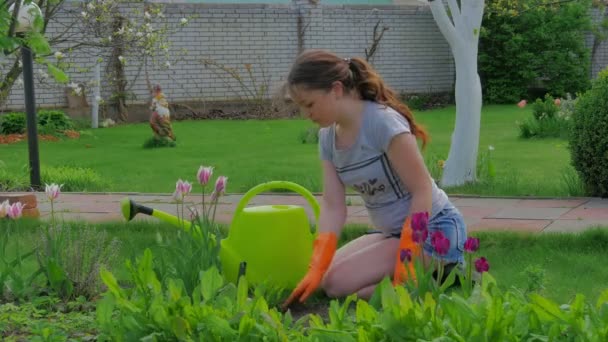小女孩与大绿色浇灌能工作在庭院在夏天时间 — 图库视频影像