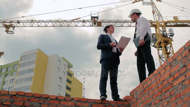 Zakenlieden in helmen voor de bouw van gebouwen — Stockvideo