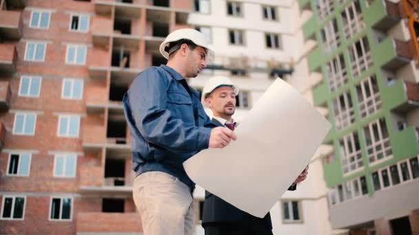 Бизнесмены в шлемах на строительстве зданий — стоковое видео