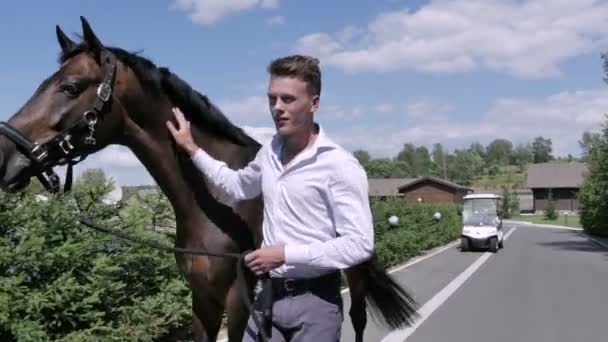 Hombre caminando con caballo en el camino — Vídeo de stock