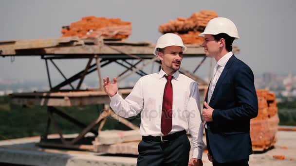 Hombres de negocios en cascos en la construcción de edificios — Vídeo de stock